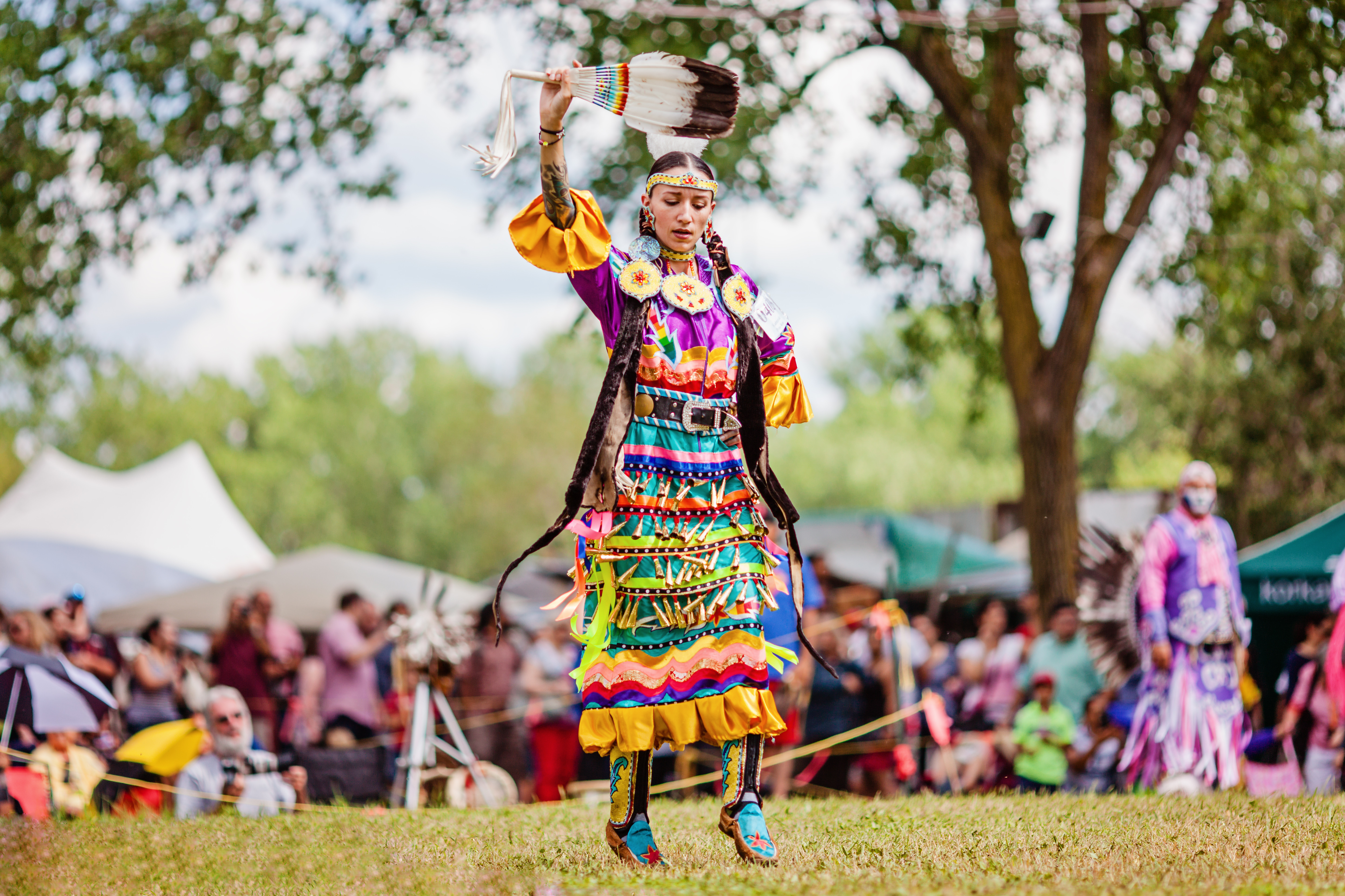 Brightly colored imagine of a jingle dress dancer performing at a Pow Wow